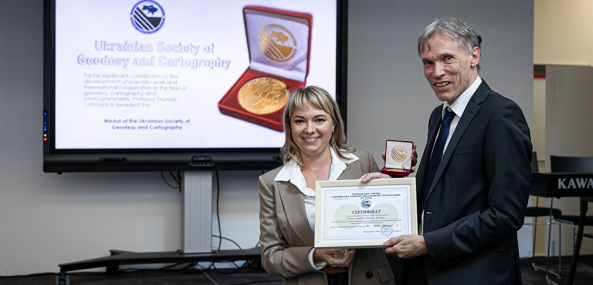 Dr. Julia Gorkovchuk, Kiewer Nationale Universität für Bauwesen und Architektur, verleiht die Gold-Medaille an Prof. Dr. Thomas Luhmann. (Foto: Jade HS/Andreas Rothaus)